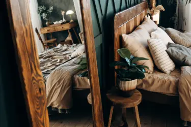 A bed with bedside table reflected in a mirror