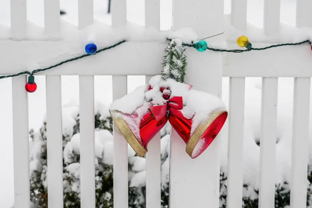 White fence with jingle bells and multi-colored string lights