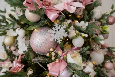 centre of artificial Christmas tree decorated with pink decorations bows baubles white glitter snowflake